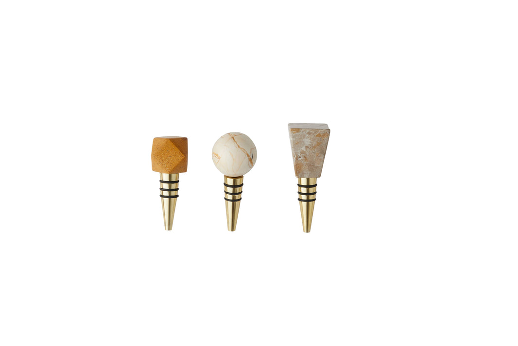 The Geometric Marble Bottle Stoppers, Set of 3, features handmade Indian stoppers with faceted tan, round Agra marble, and rectangular beige tops on brass bases, displayed side by side on a white background.