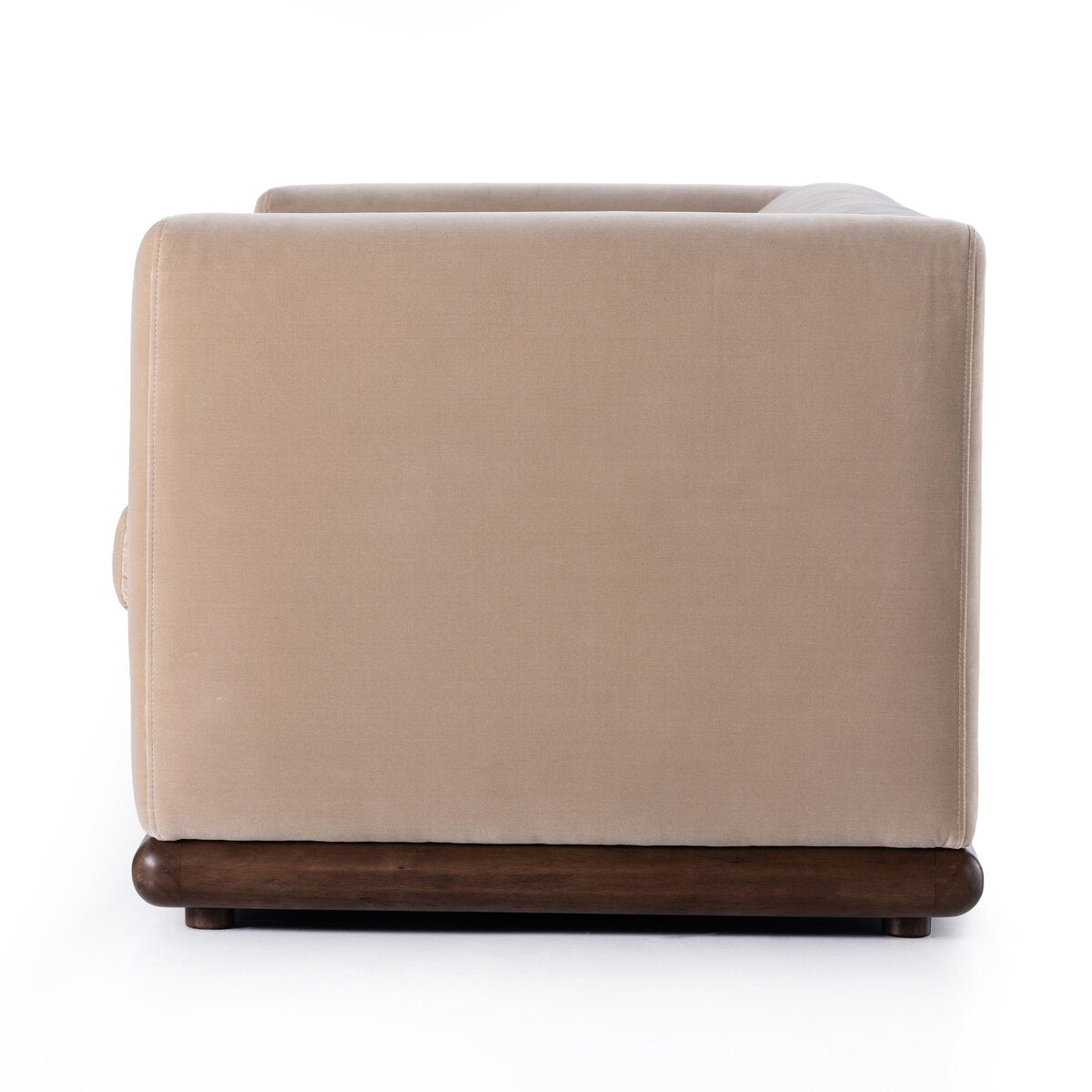 Side view of the Deco Sofa in velvety taupe upholstery with a parawood plinth base, displayed against a white background. The sofa showcases clean lines and a boxy, modern silhouette.