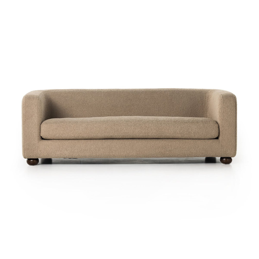 The Faux Shearling Sofa features modern beige upholstery, a low back, rounded arms, a single seat cushion, and short dark wooden legs for a vintage-inspired look, shown against a white background.