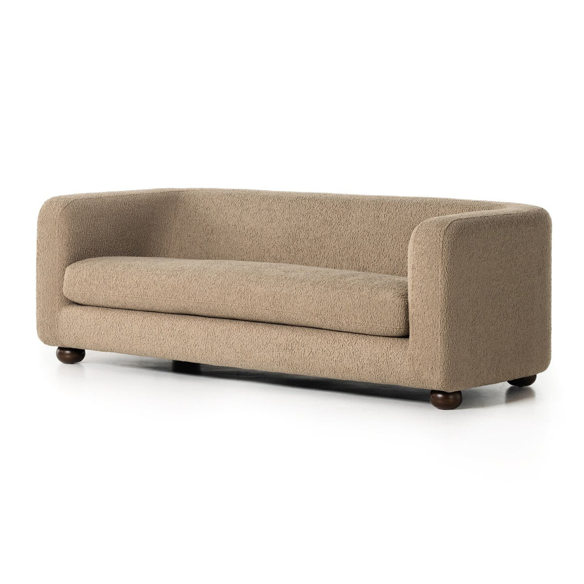 The Faux Shearling Sofa is a modern, minimalist beige sofa with rounded edges, a low backrest, textured camel upholstery, and short dark wooden legs, shown against a white background.