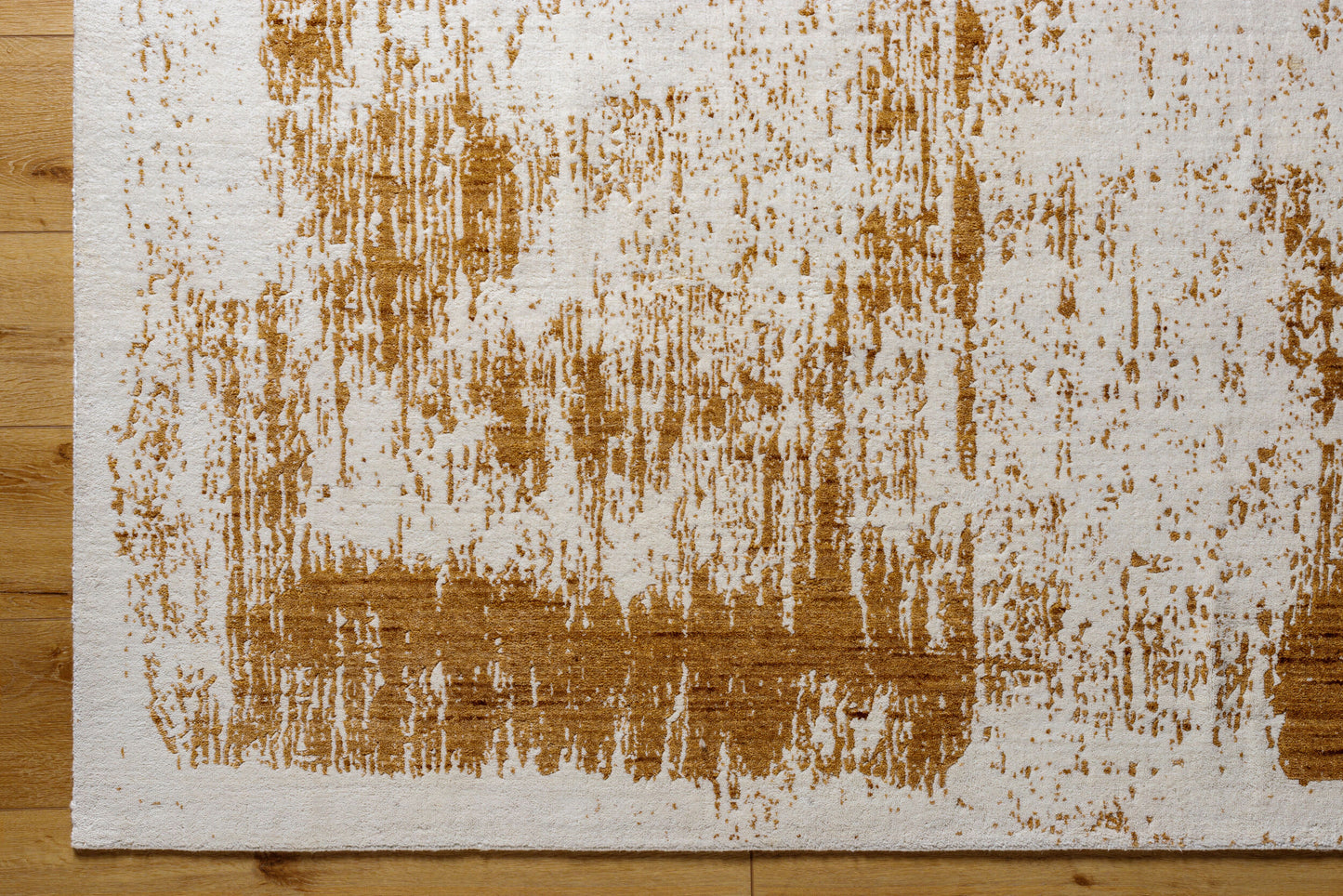 A close-up of the Abstract Color Splash Rug (8x10) on a light wooden floor, featuring irregular, brushstroke-style brown markings on a white background for an artistic, modern look.