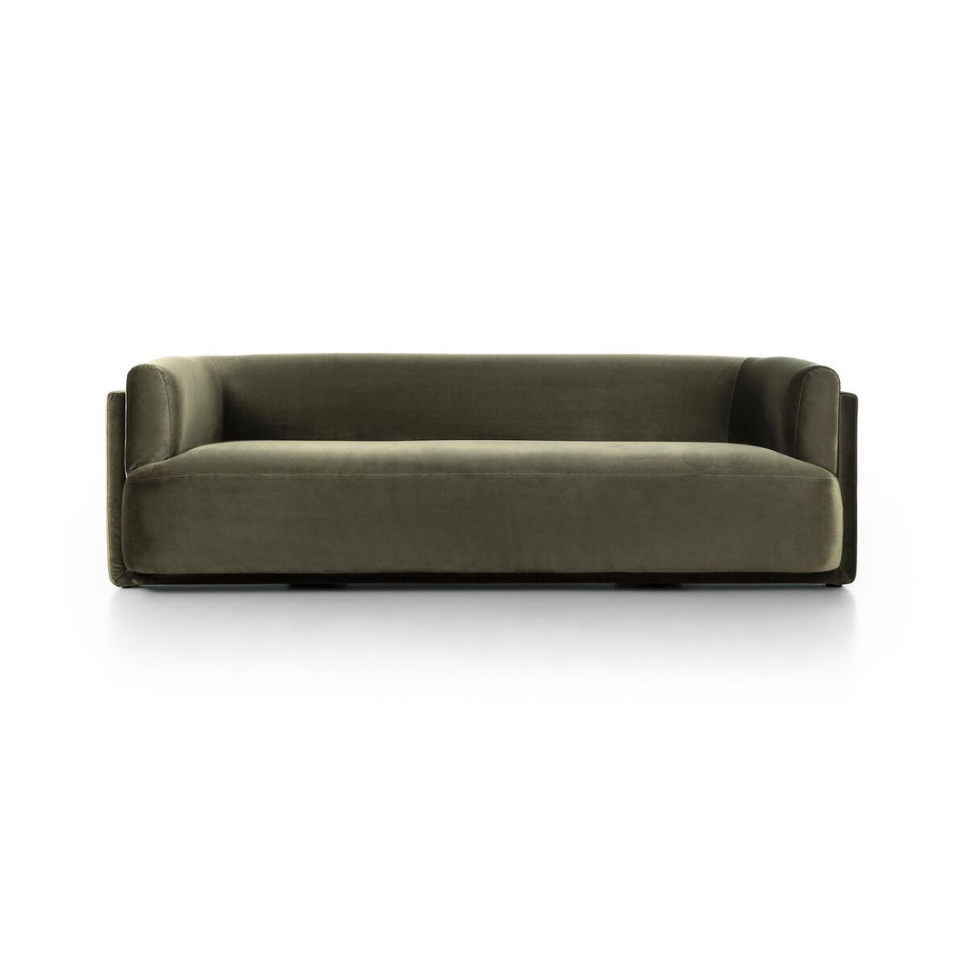 The Exposed Frame Sofa is a modern, olive green velvet piece with full upholstery, low back and arms, and a minimalist boxy design, displayed against a plain white background.