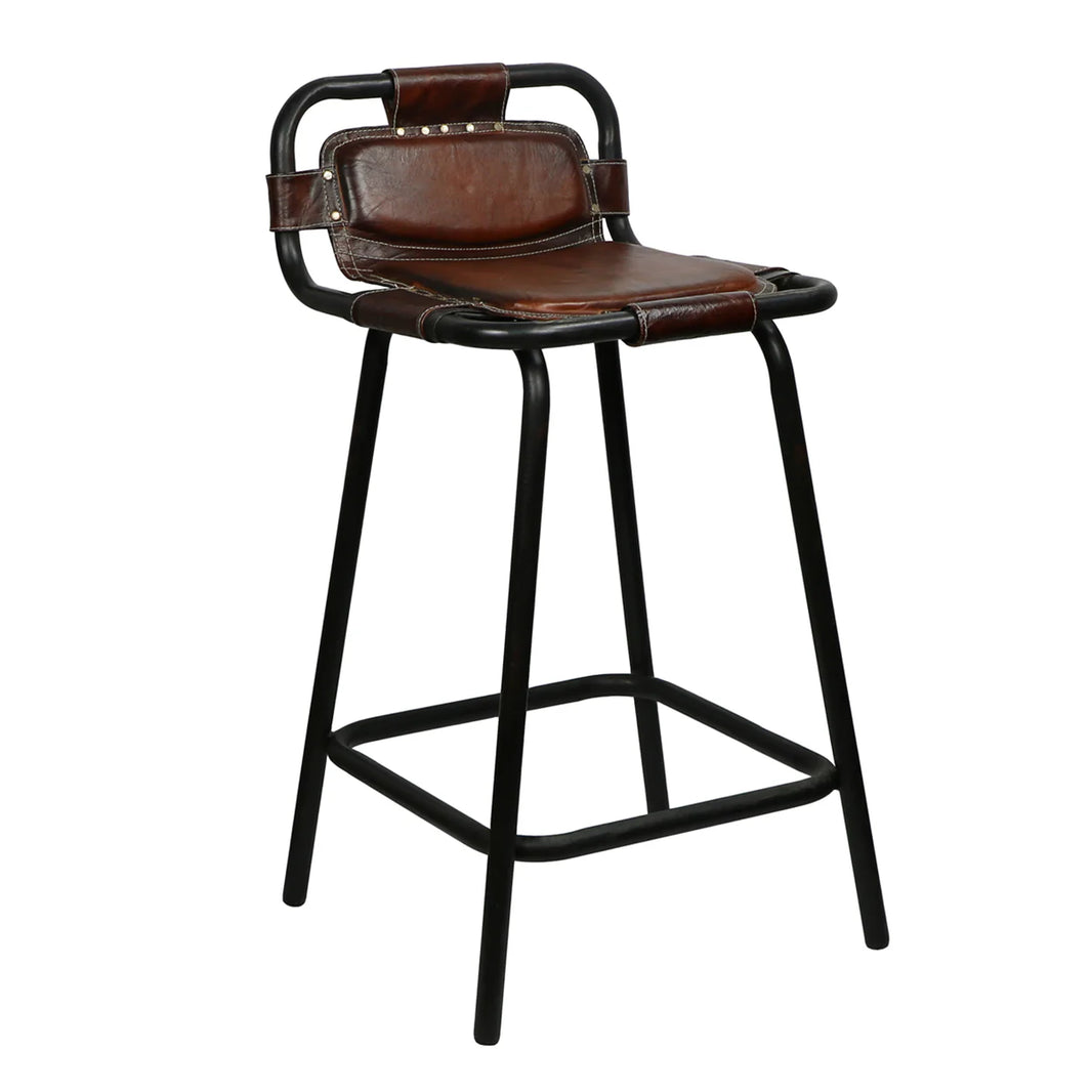 The Stitched Leather Stool features a modern, minimalist industrial design with a black metal frame, brown padded leather seat, matching leather backrest, and a convenient footrest.