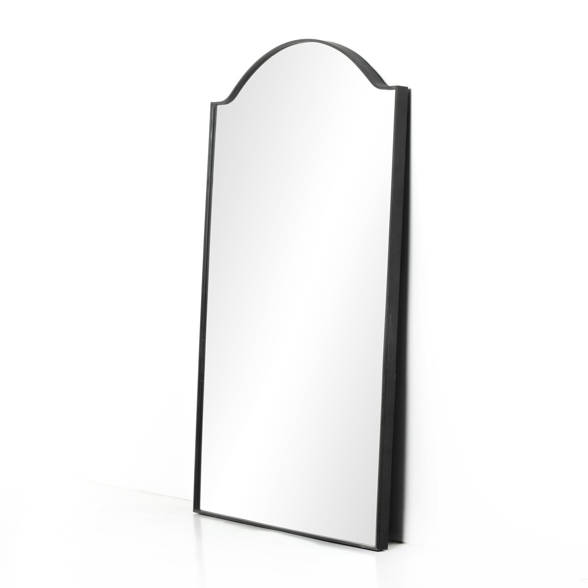 The Jacques Floor Mirror, a tall rectangular mirror with an arched black frame measuring 62.00"w x 84.00"h, leans against a white wall on a white floor.