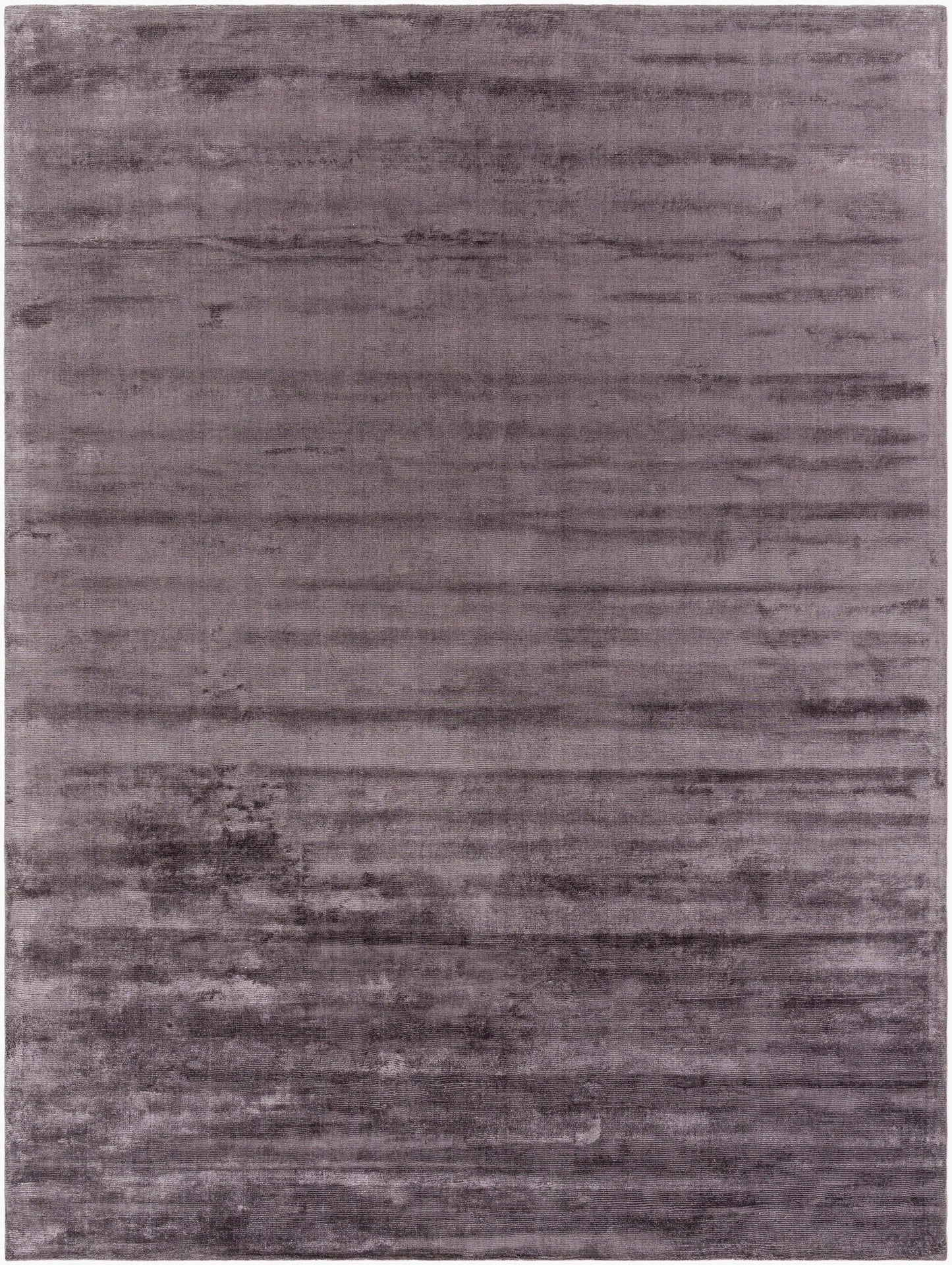 The Striped Cord Rug 8 x 10 has a soft, velvety texture with subtle horizontal stripes, featuring varying shades of purple and lavender in a slightly mottled design.