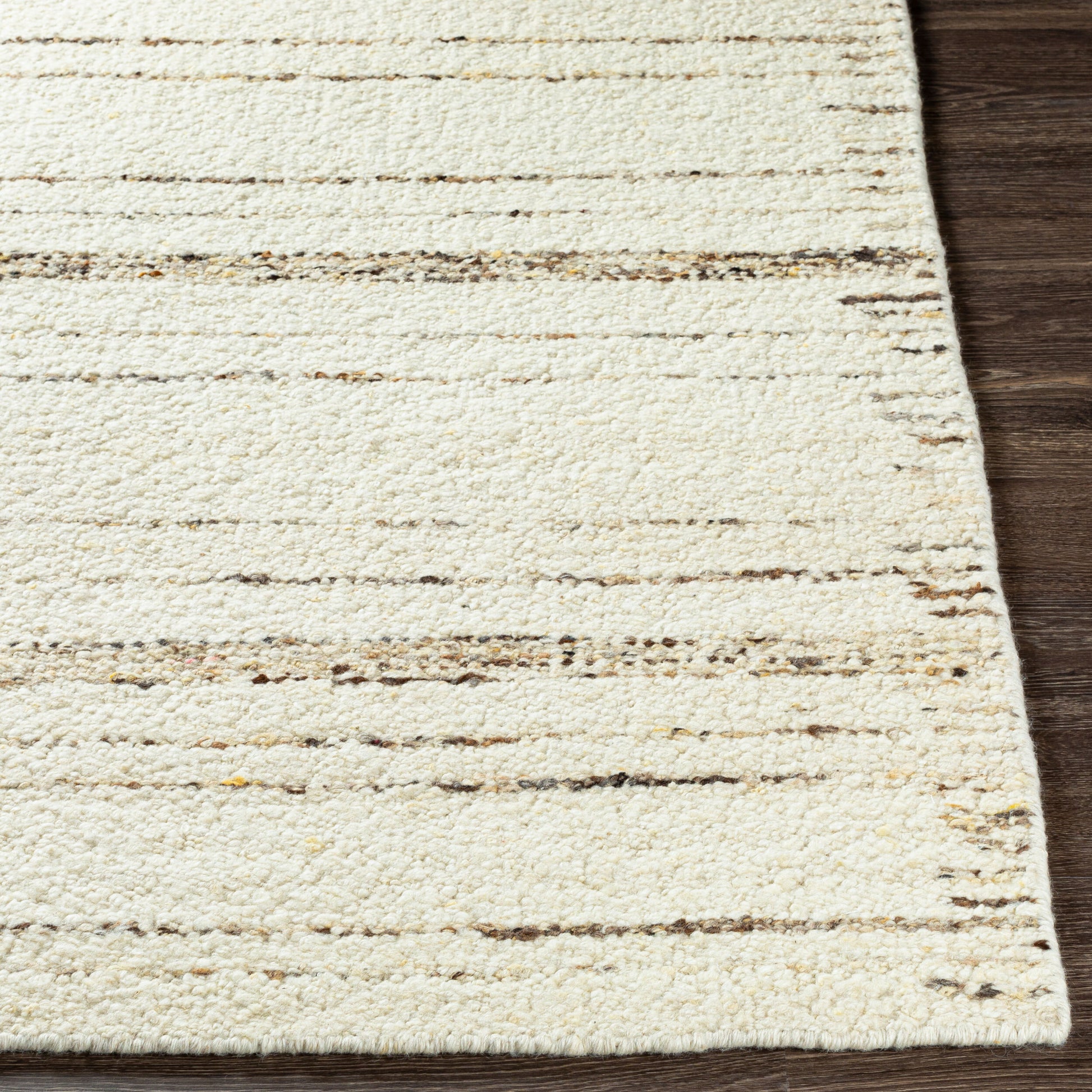 A close-up of the Thin & Thick Line Stripe Rug – 8 x 10, a handwoven wool rug in cream with subtle brown and beige horizontal stripes, shown on a dark wooden floor.