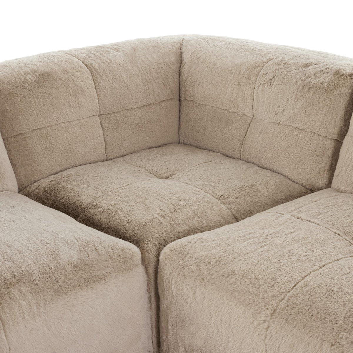 A close-up of the Plush Sectional - 7pc in beige showcases its soft, textured fabric, visible seam stitching, and S-spring suspension for enhanced comfort.