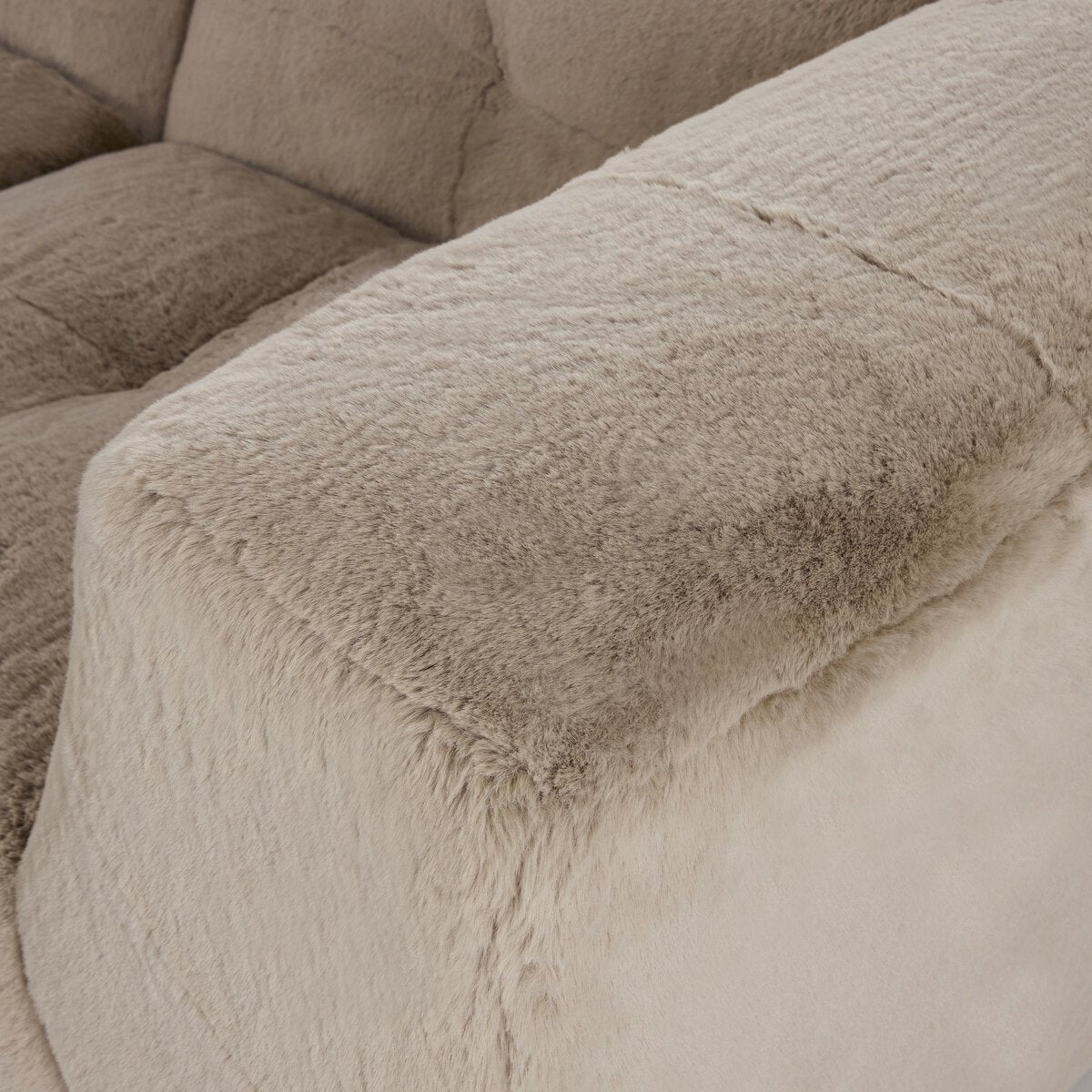 Close-up of the Plush Sectional - 7pc armrest, showcasing its soft, fuzzy upholstery and detailed seams, with an additional cushion in the background.