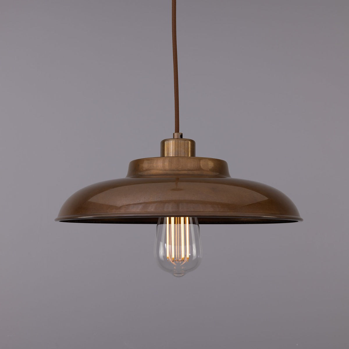 The Industrial Brass Pendant Light features a 12.5″ diameter dome-shaped metal shade in a bronze finish, an exposed filament bulb, and hangs from a 40″ chain against a plain gray background.