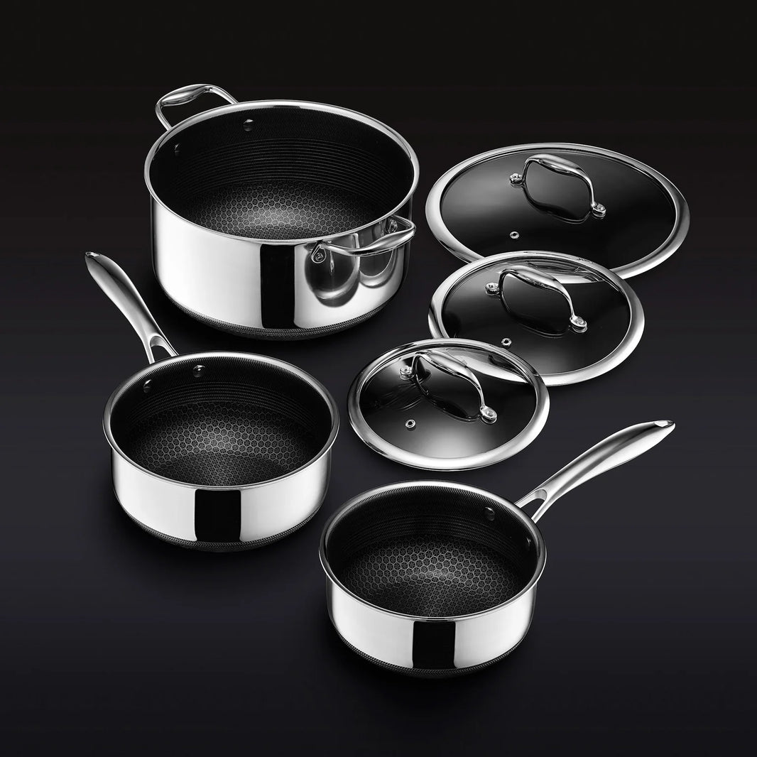 The Hexclad Pot Set with Lids features three stainless steel saucepans, each with a shiny exterior, hexagonal-patterned black nonstick interior, sturdy metal handles, and matching lids, all shown on a black background.