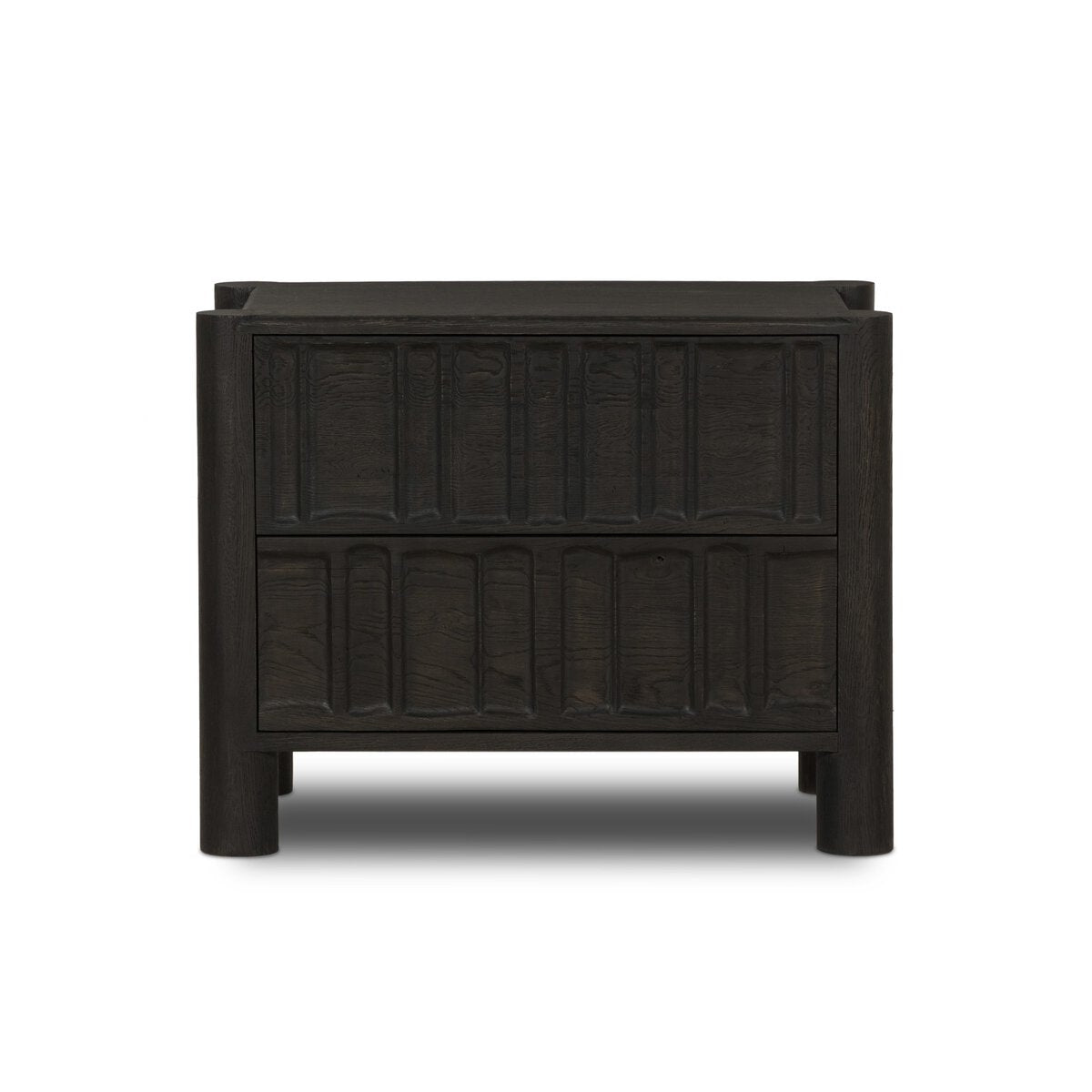 The Primitive Nightstand, crafted from cocoa-finished oak, features two drawers with vertical organic carvings and sleek cylinder legs, displayed against a white background.
