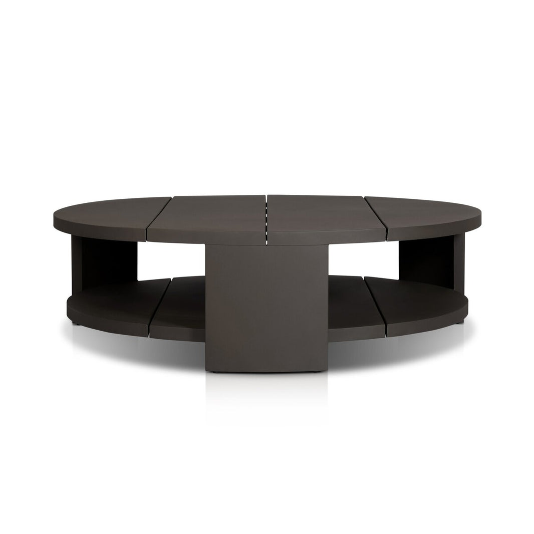 The Bronze Finished Aluminum Round Coffee Table features a modern, sculptural design with a dark finish, an open lower shelf, central square support, and segmented top and bottom surfaces for a striking look.