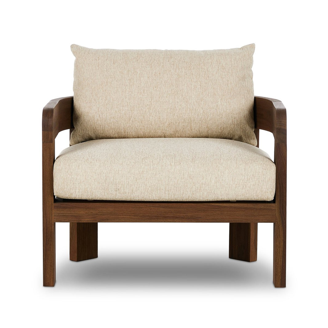 The Barrel Back Outdoor Chair features warm beige upholstery, sturdy teak framing, wide armrests, and a minimalist design, showcased against a white background.
