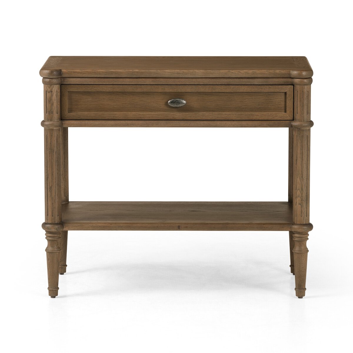 The European Nightstand features a single central drawer with a round metal handle, a lower open shelf, and turned legs. Its warm medium-brown wood finish enhances the timeless, vintage-inspired design.