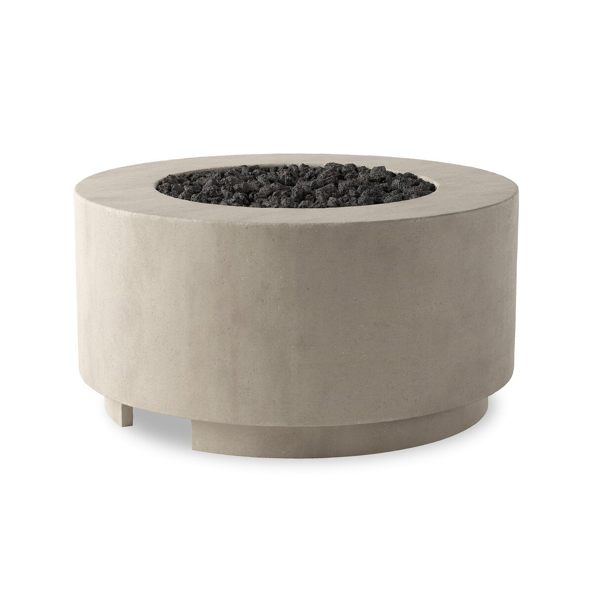 The Damian Outdoor Fire Table is a round, modern concrete fire pit in light gray with short legs and a central recessed area filled with black lava rocks, resembling a coffee table.