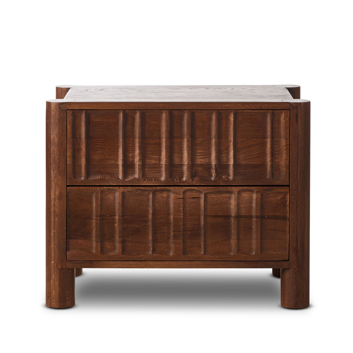 The Primitive Nightstand, crafted in cocoa-finished oak, features two textured drawers, rounded corners, vertical grooves, and cylinder legs for a modern look, shown against a white background.