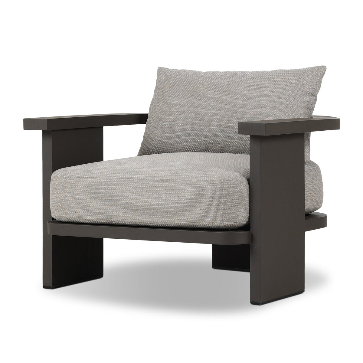 The Three Legged Outdoor Chair features a minimalist, boxy design with thick light gray high-performance cushions and wide, flat black wooden armrests and frame.