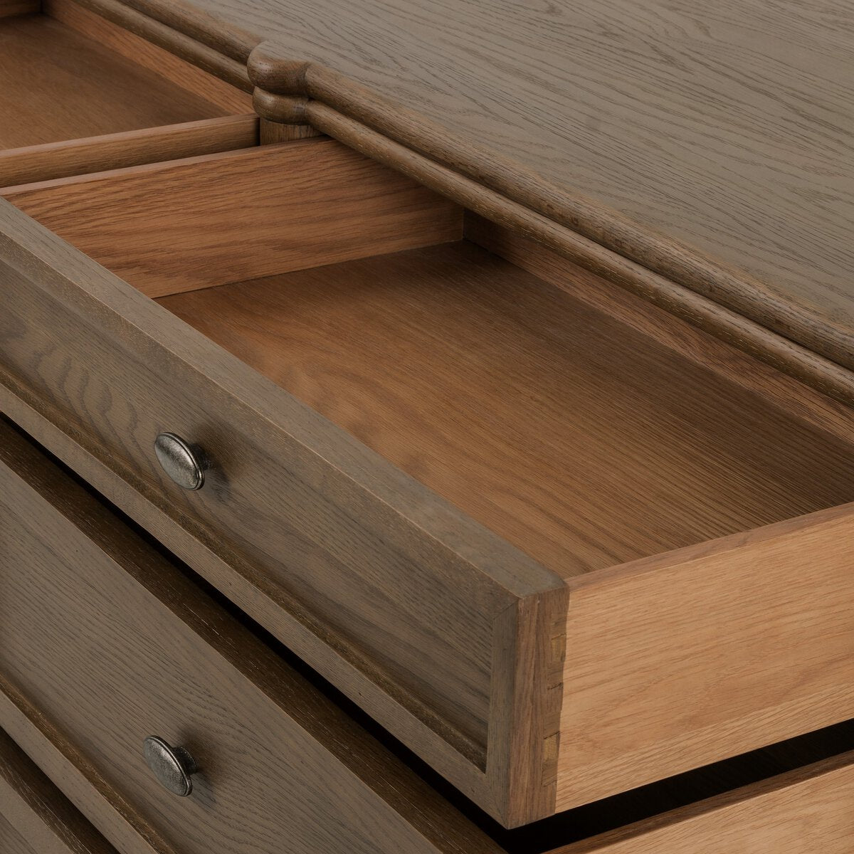 A close-up of the European 9 Drawer Dresser shows three partially open drawers with smooth, natural wood interiors and round metal pulls. This dresser features a simple, classic design, ideal for modern bedroom decor.