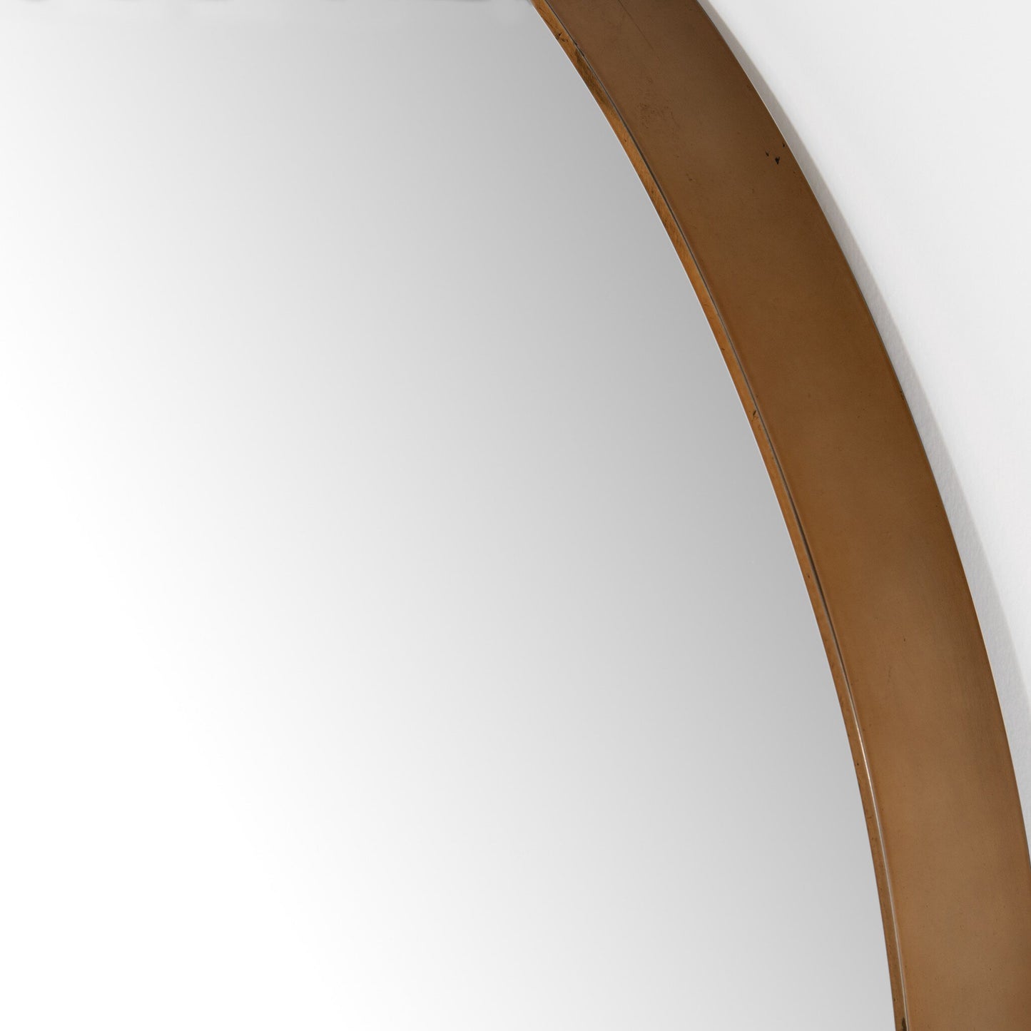 Close-up of the Georgina Floor Mirror's thick bronze metallic frame against a white background. Only part of its 32-inch wide, large round design is visible, emphasizing its substantial size and elegant look.