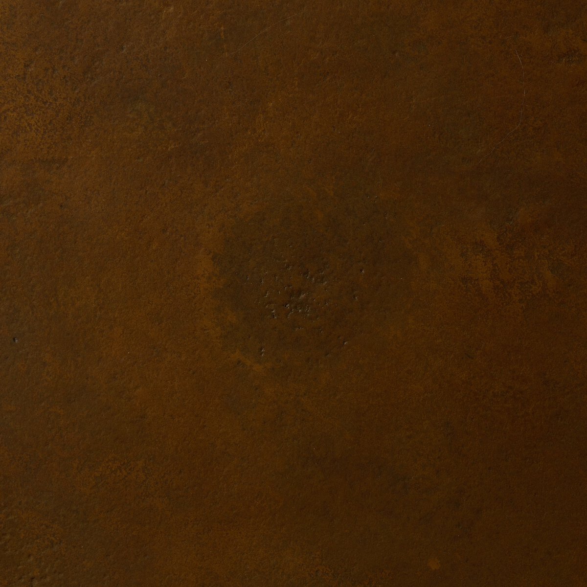 A close-up of the Copper-Toned Outdoor End Table shows its textured, rusted metal surface with brownish-orange hues and varied shading, evoking an antiqued look perfect for modern outdoor spaces.