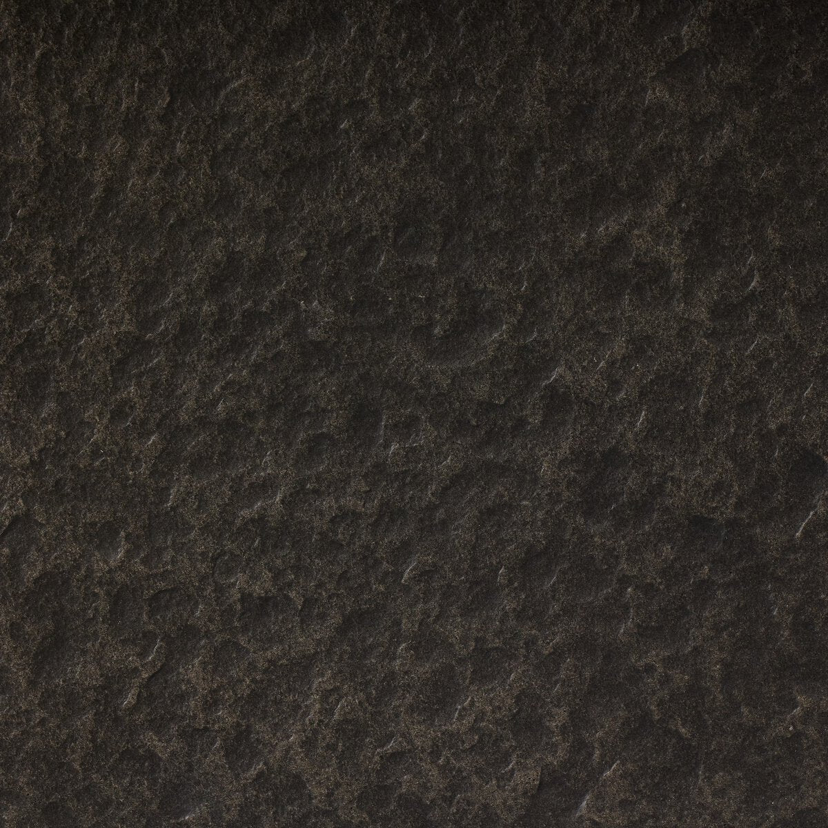 The Distressed Coffee Table features a dark, textured stone surface with rough, uneven patterns and subtle color variations, reminiscent of distressed graphite.