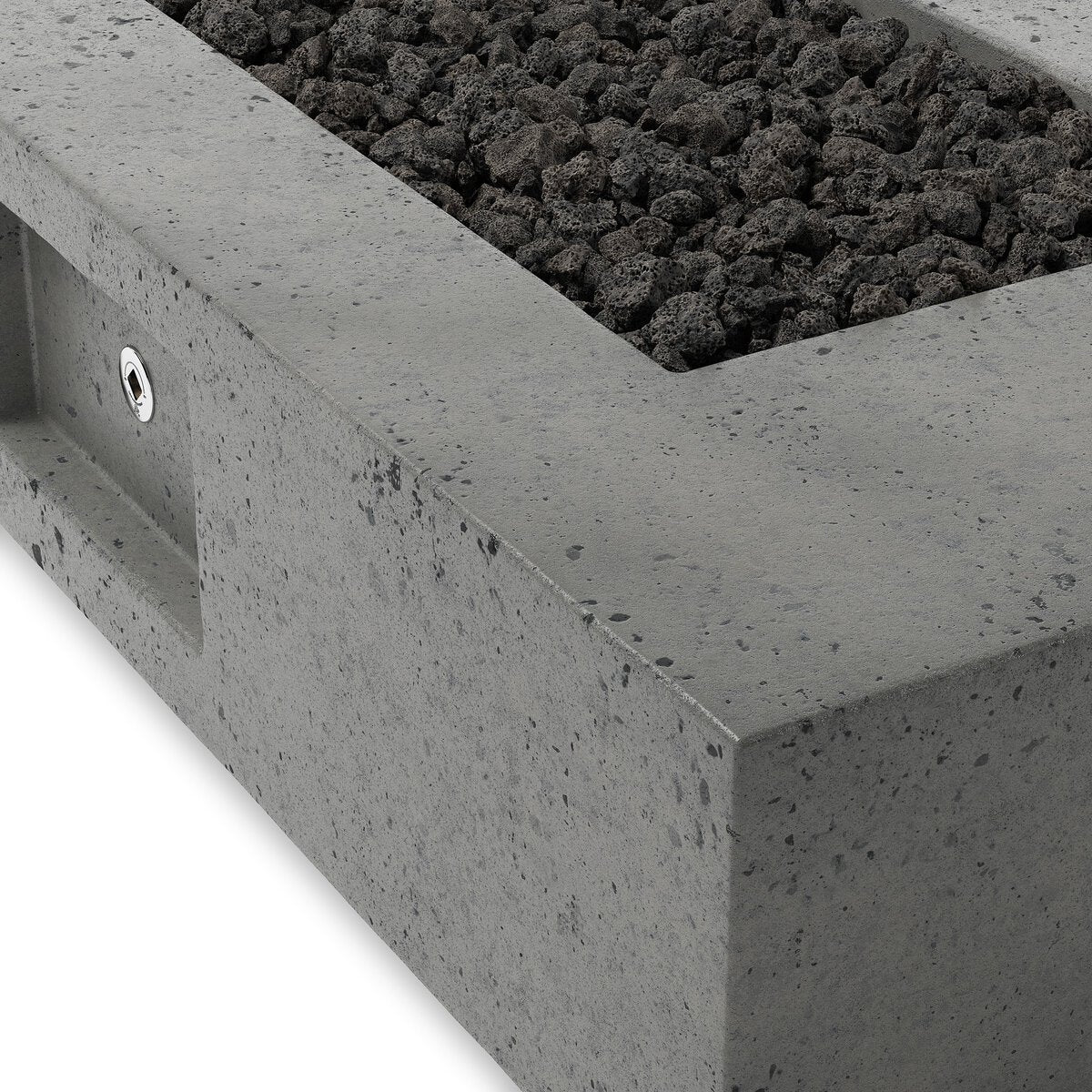Close-up of the Outdoor Fire Table with a rectangular glass-reinforced concrete build, recessed area filled with black lavastones, textured surface, and a small round metal control on the side.