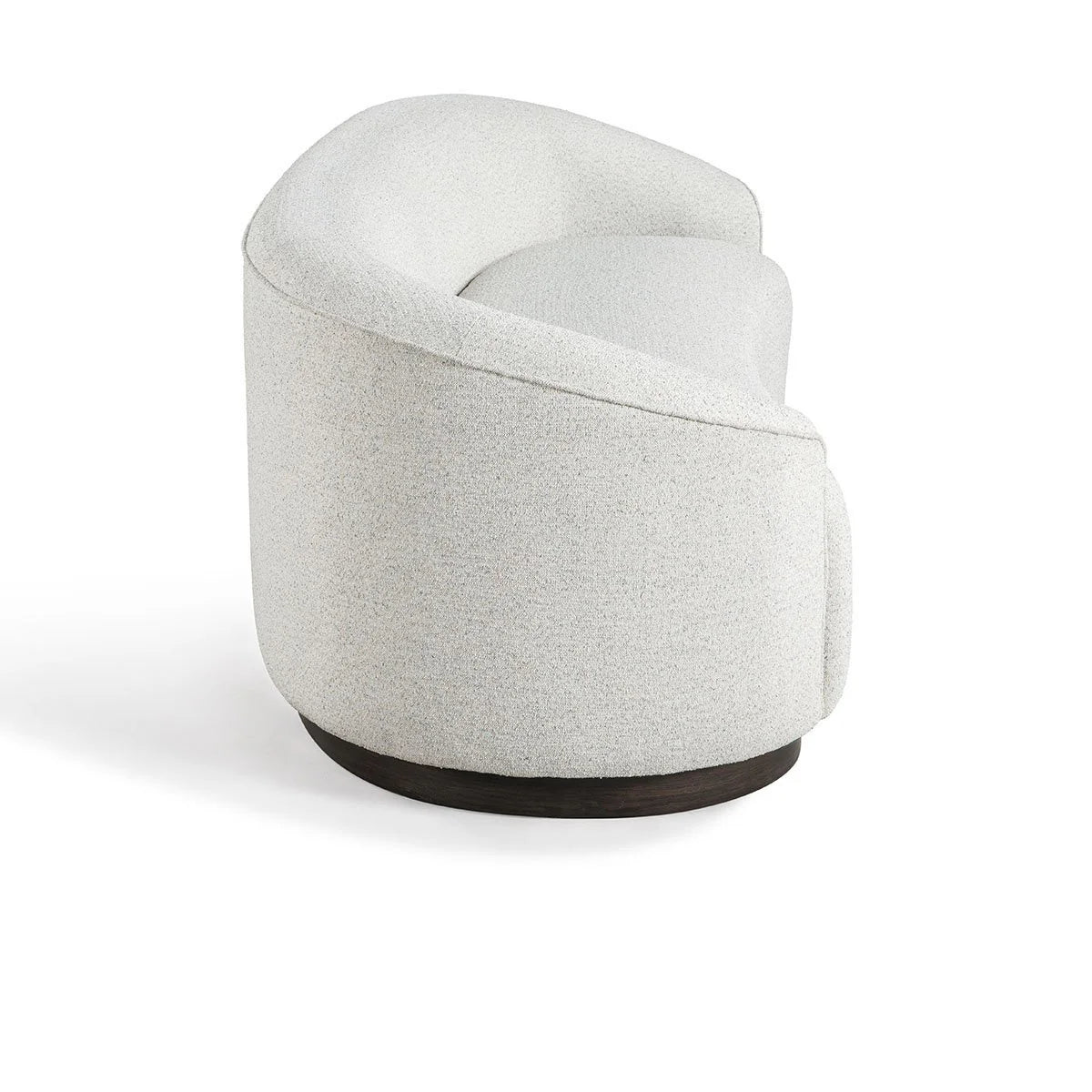 The Curved Sofa features a modern sculptural design with curved lines, light textured upholstery, and a dark circular wooden base, shown against a white background.