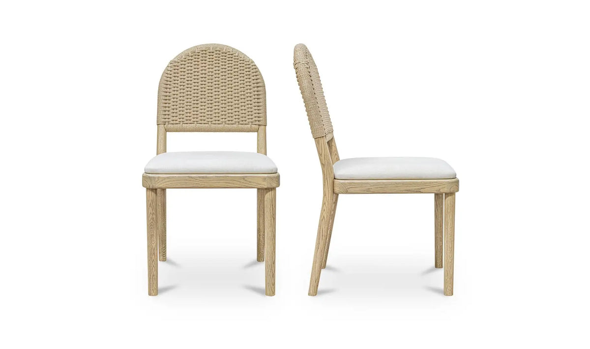 The Natural Oak Dining Chair - Set of Two is displayed on a white background, with one chair facing forward and the other in profile to showcase its wooden frame, rounded woven back, and light cushioned seat.