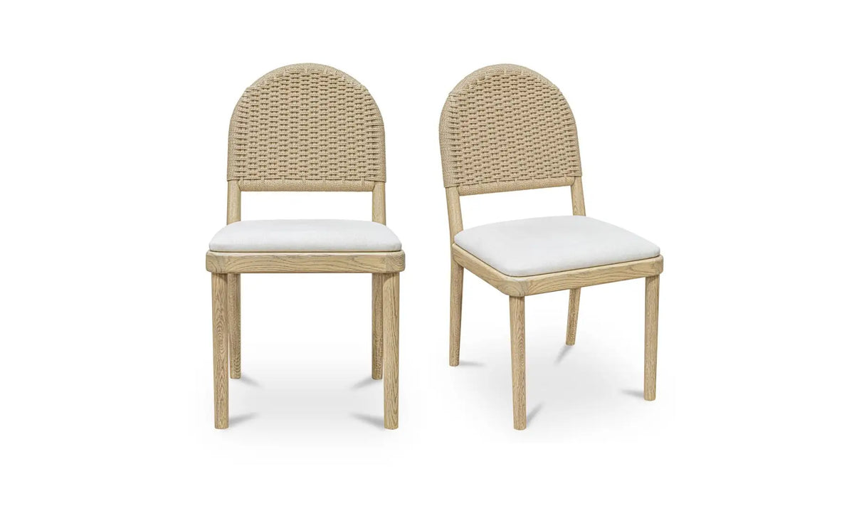 The Natural Oak Dining Chair - Set of Two features wooden frames with rounded, woven rattan backs and white seat cushions—versatile seating perfect for any space.
