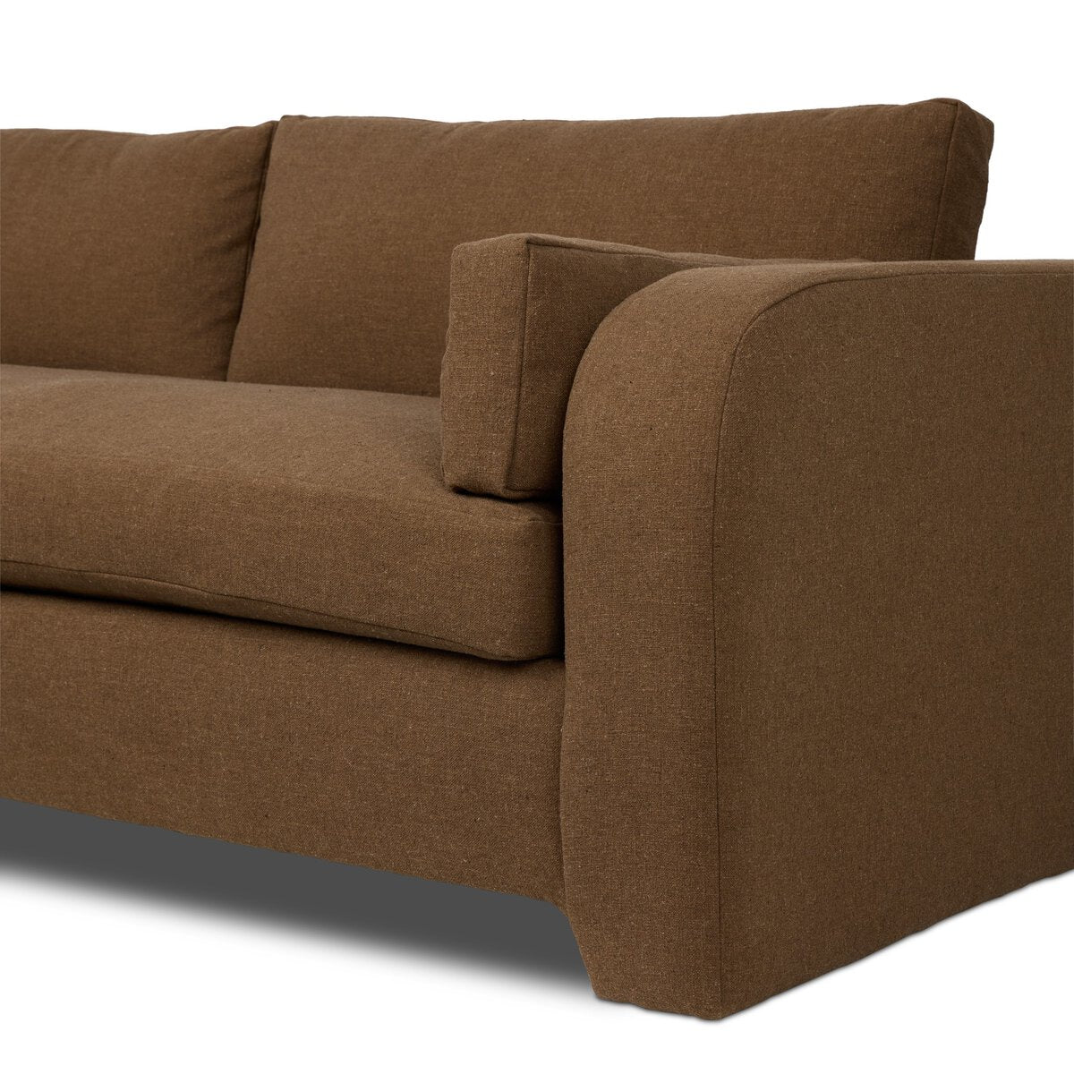 The Arched Arms Sectional features a brown coffee hue with thick seat and back cushions, extra padding, a wide rounded right armrest, and a matching rectangular pillow. Only part of the sectional is shown.