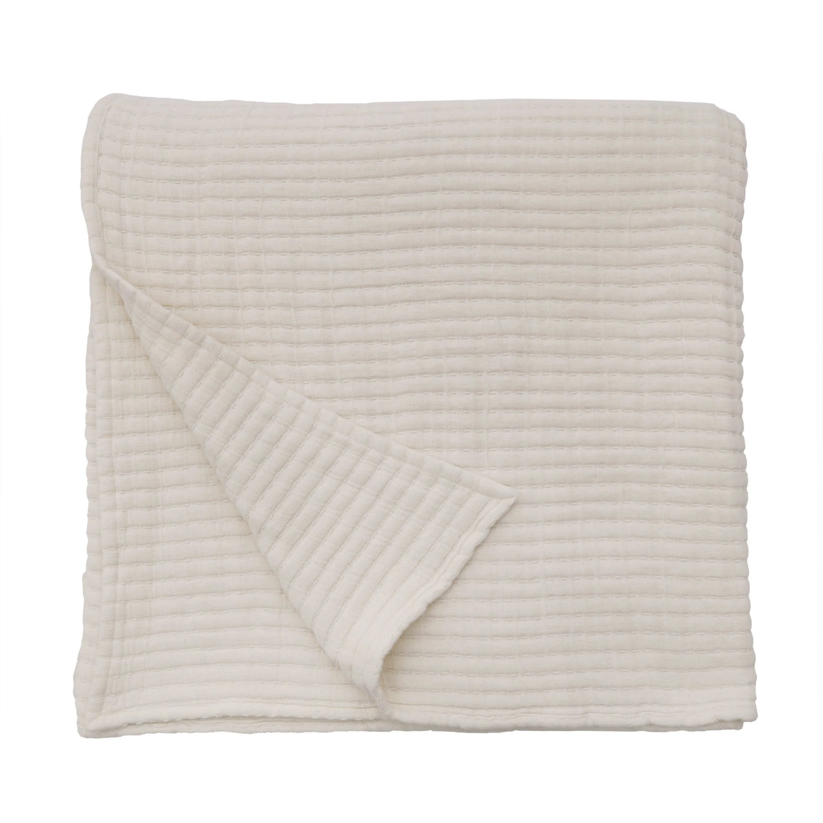 A cream cotton oversized throw blanket with a folded, textured design and a slightly turned corner, highlighting its soft, quilted fabric and generous 60 x 90″ dimensions.