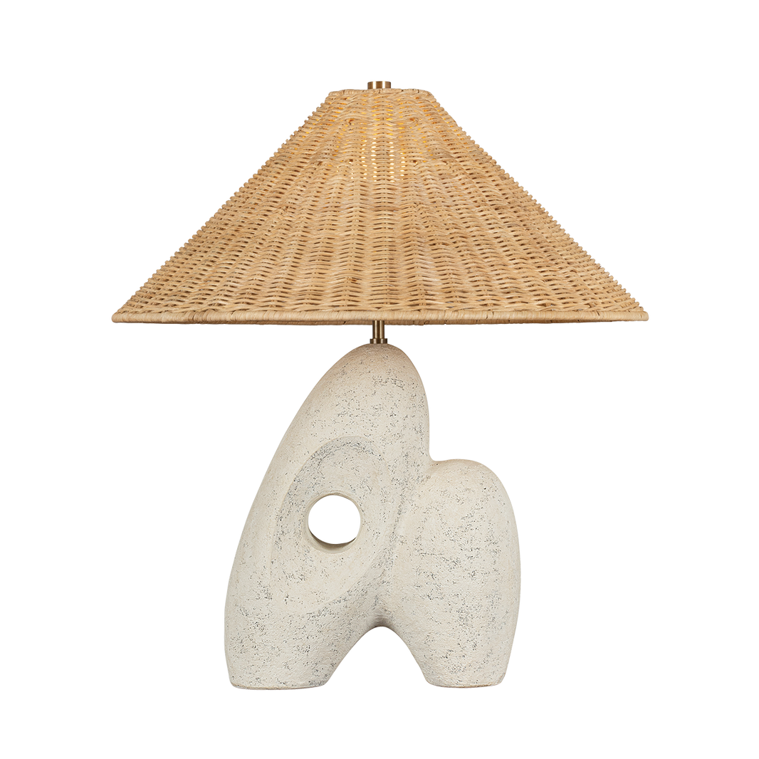 The Stone and Woven Table Lamp features a sculptural white base with an abstract design and hole, paired with a wide 22" woven rattan cone shade. Overall height is 24.5". Shown against a plain white background.
